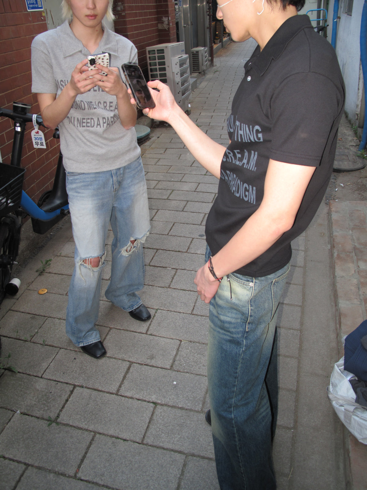 Two models in graphic polo shirts and denim on a Seoul street