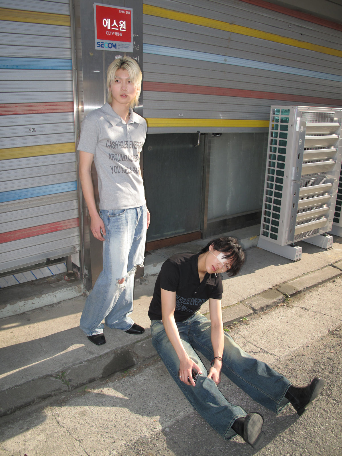 Two models wearing graphic polo shirts and wide-leg denim in Seoul