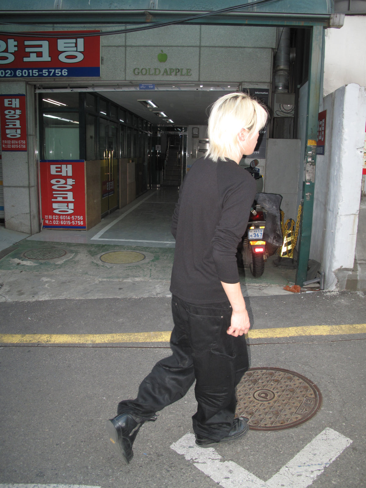 Blond model in a black long-sleeve top walking on a Seoul street
